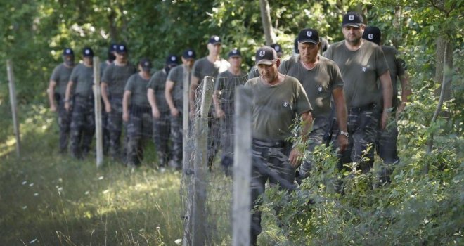 Ljudi u paravojnim uniformama paradiraju uz granicu: Jedni nose ruske zastave, a drugi kape domobrana